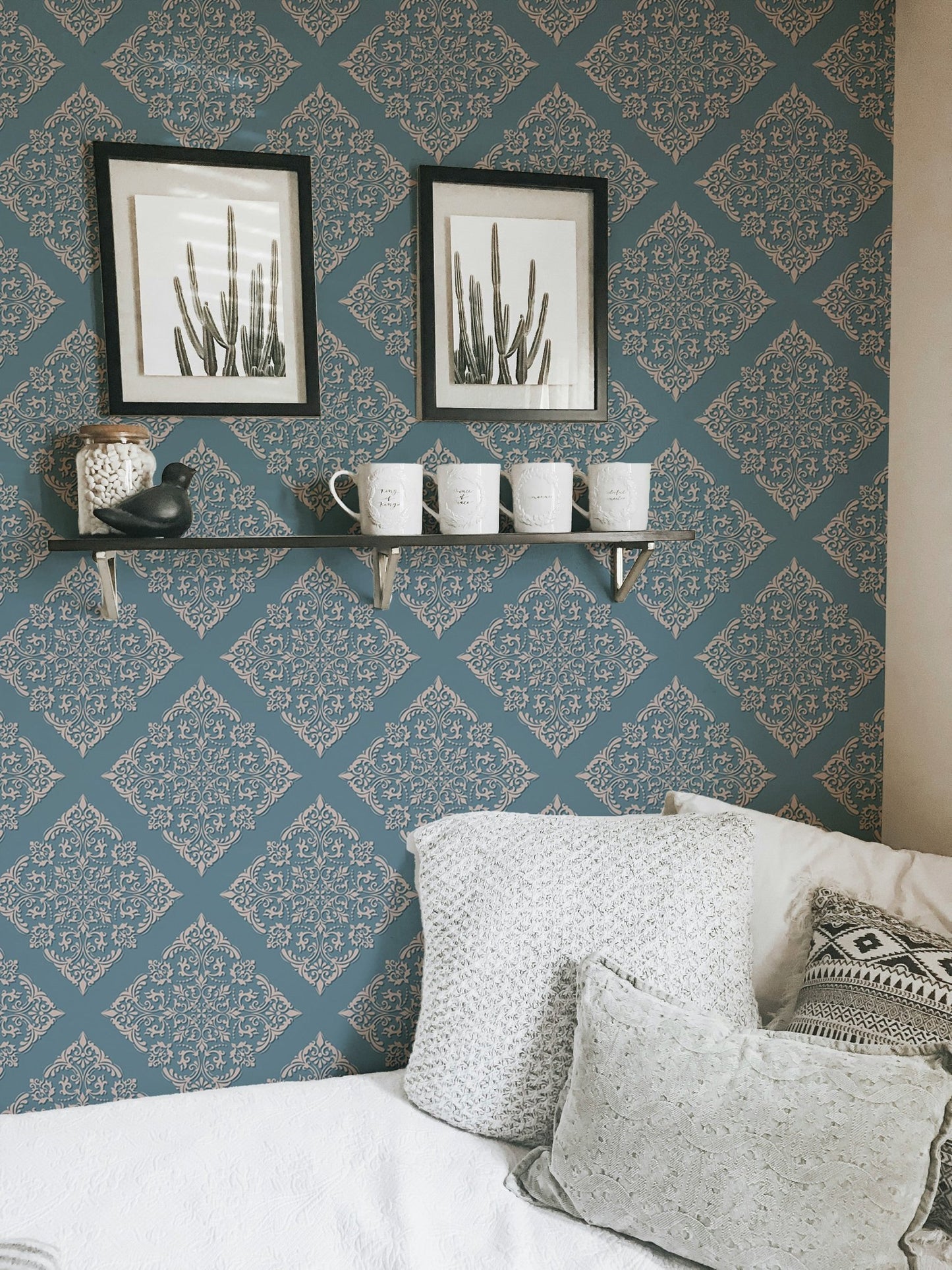 Blue color wallpaper in small bedroom behind white pillows and frames.