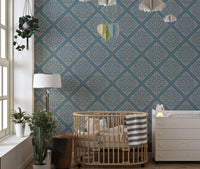 Blue damask wallpaper in nursery behind wooden crib and dresser.