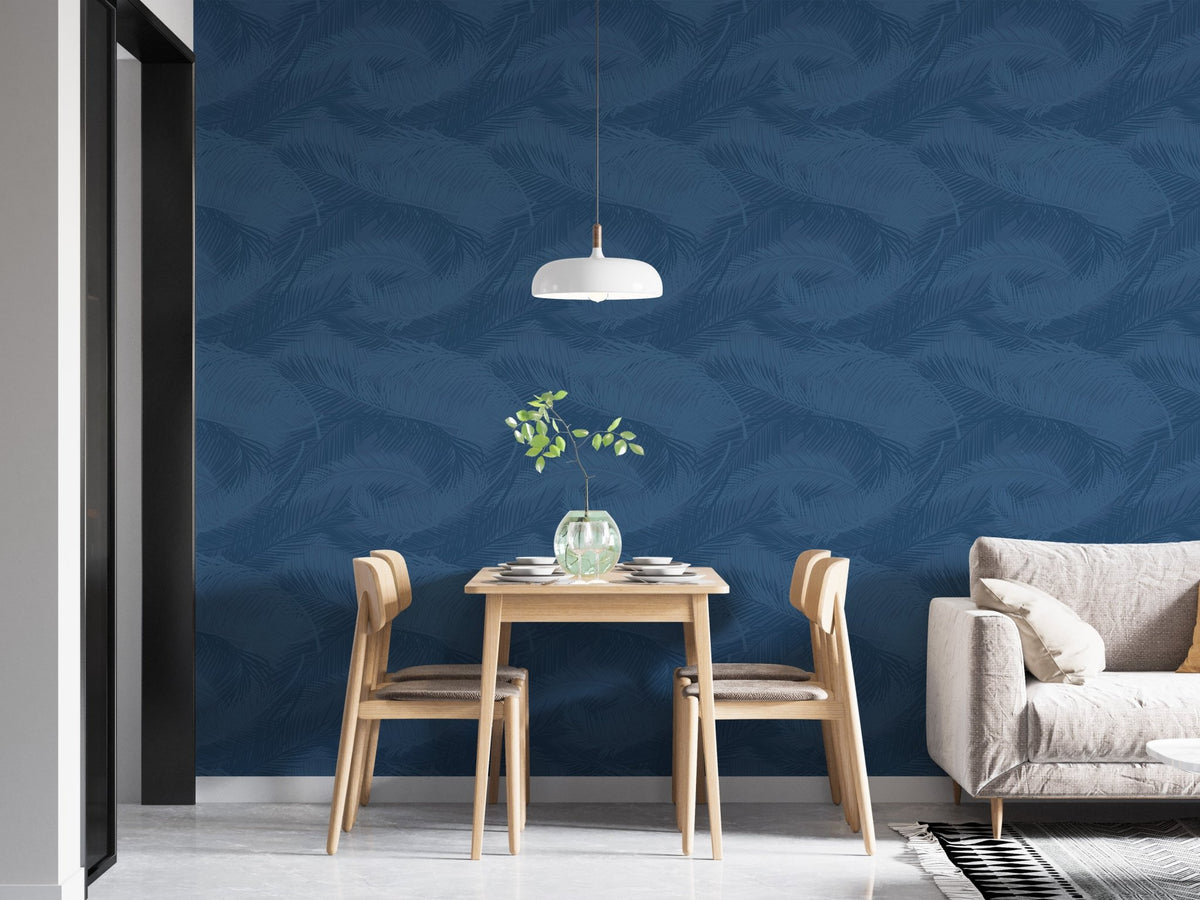 Blue Palm Leaves Silhouette Wallpaper behind wooden dining table and chairs.