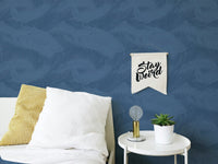Blue palm leaves silhouette removable wallpaper in a bedroom with white pillows.