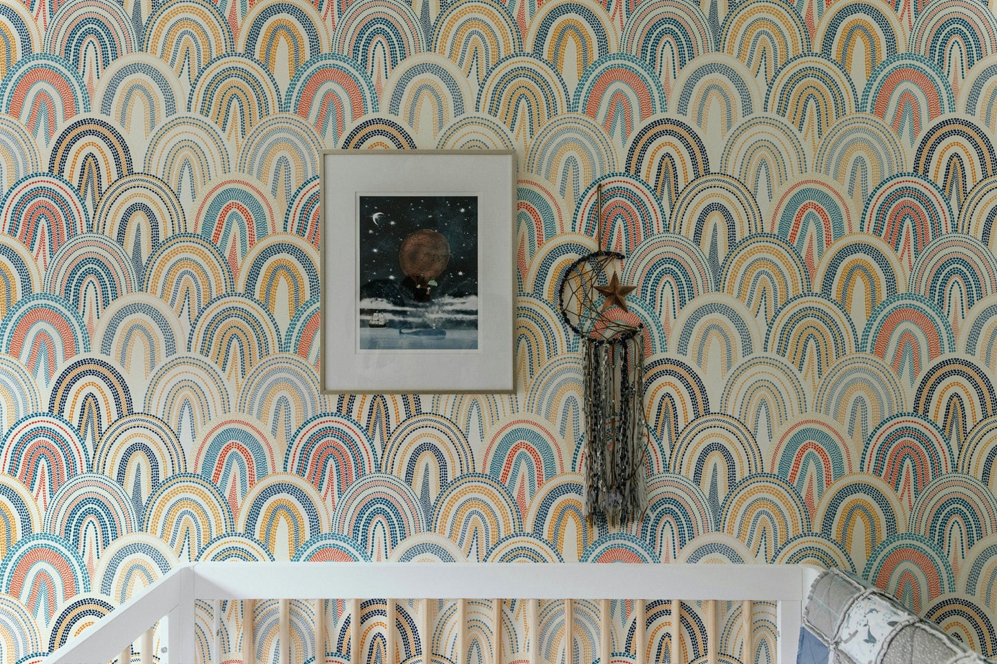 Arched geometric pattern wallpaper in a nursery with a white crib and framed art.