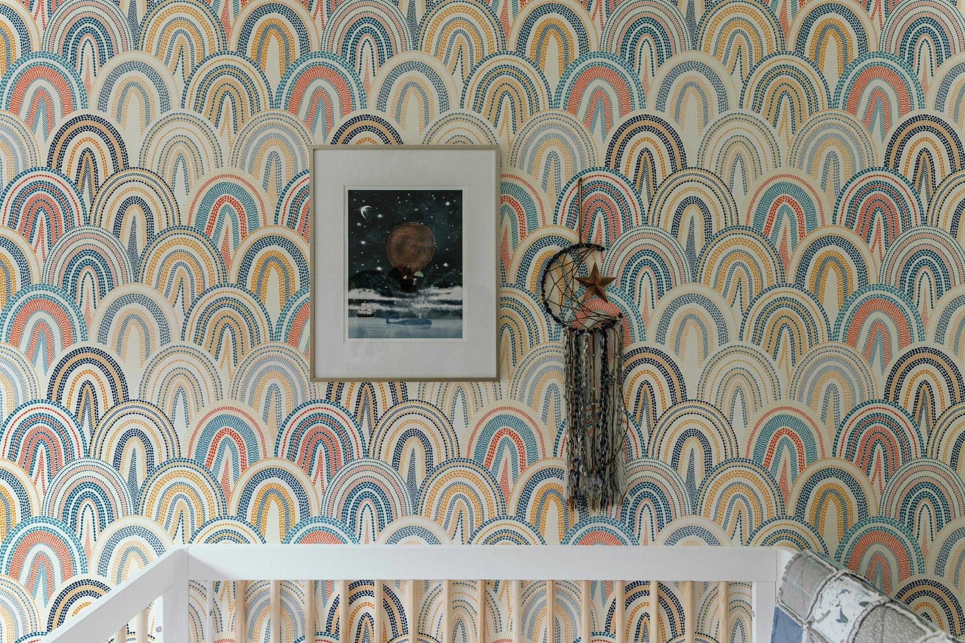 Arched geometric pattern wallpaper in a nursery with a white crib and framed art.