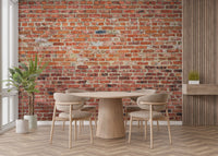 Minimalist dining space with a round table and red brick wall mural.