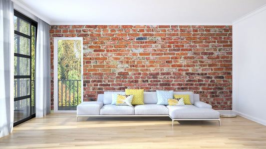 Large living room with white sectional sofa and brick wall mural.