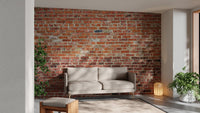 Industrial living area featuring red brick wall mural behind a tan sofa.