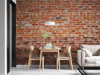Small dining nook featuring rustic red brick wall mural and white chairs.