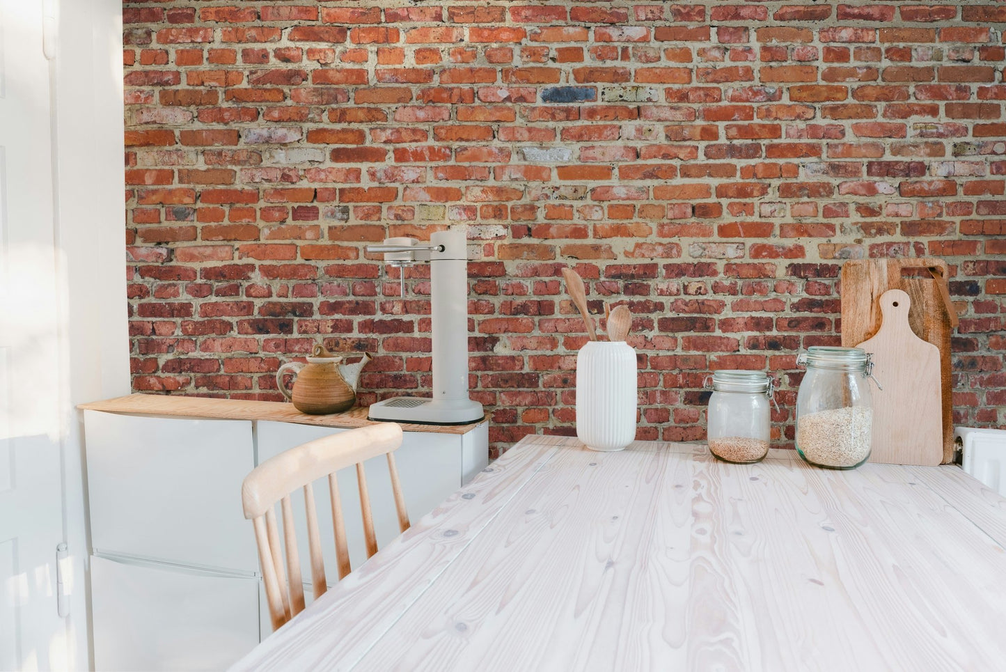 Kitchen area with white cabinets and weathered brick wall mural.