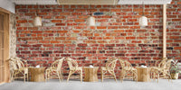 Cafe interior with wooden stools and textured brick wall mural.