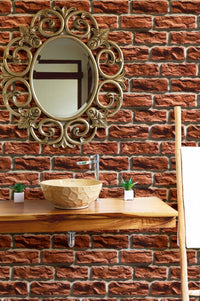 Brown brick wallpaper behind a bathroom vanity with a gold ornate mirror.