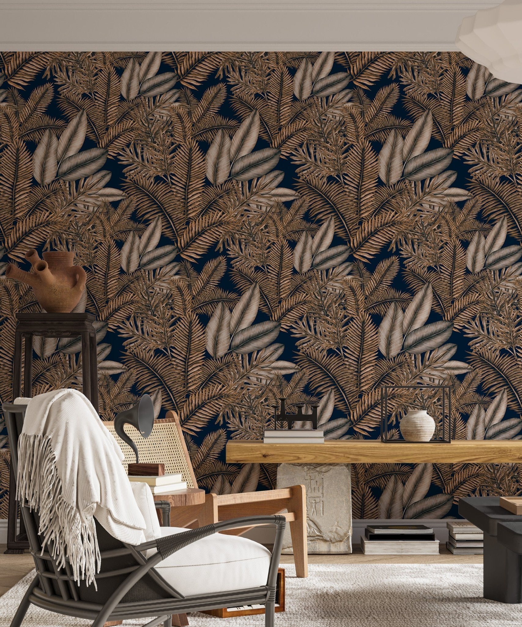 Tropical dry leaves wallpaper behind a black living area chair and wooden desk.