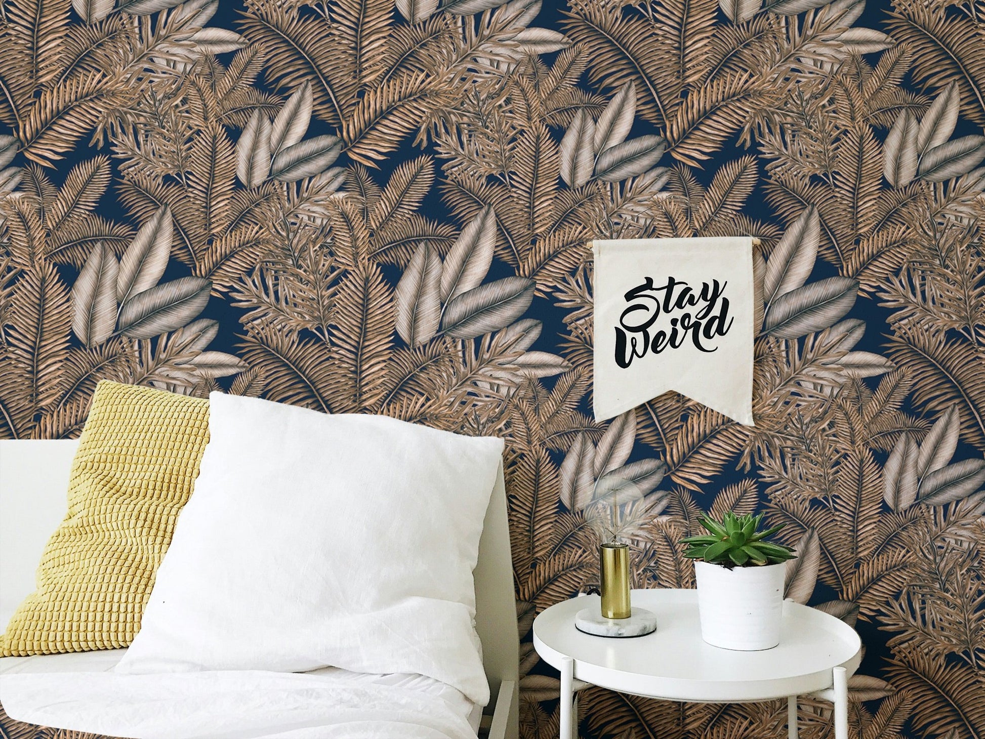 Seamless pattern tropical dry leaves wallpaper behind a white bed and pillow.