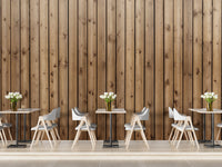 Narrow wood strip wall mural behind small cafe tables and white chairs.