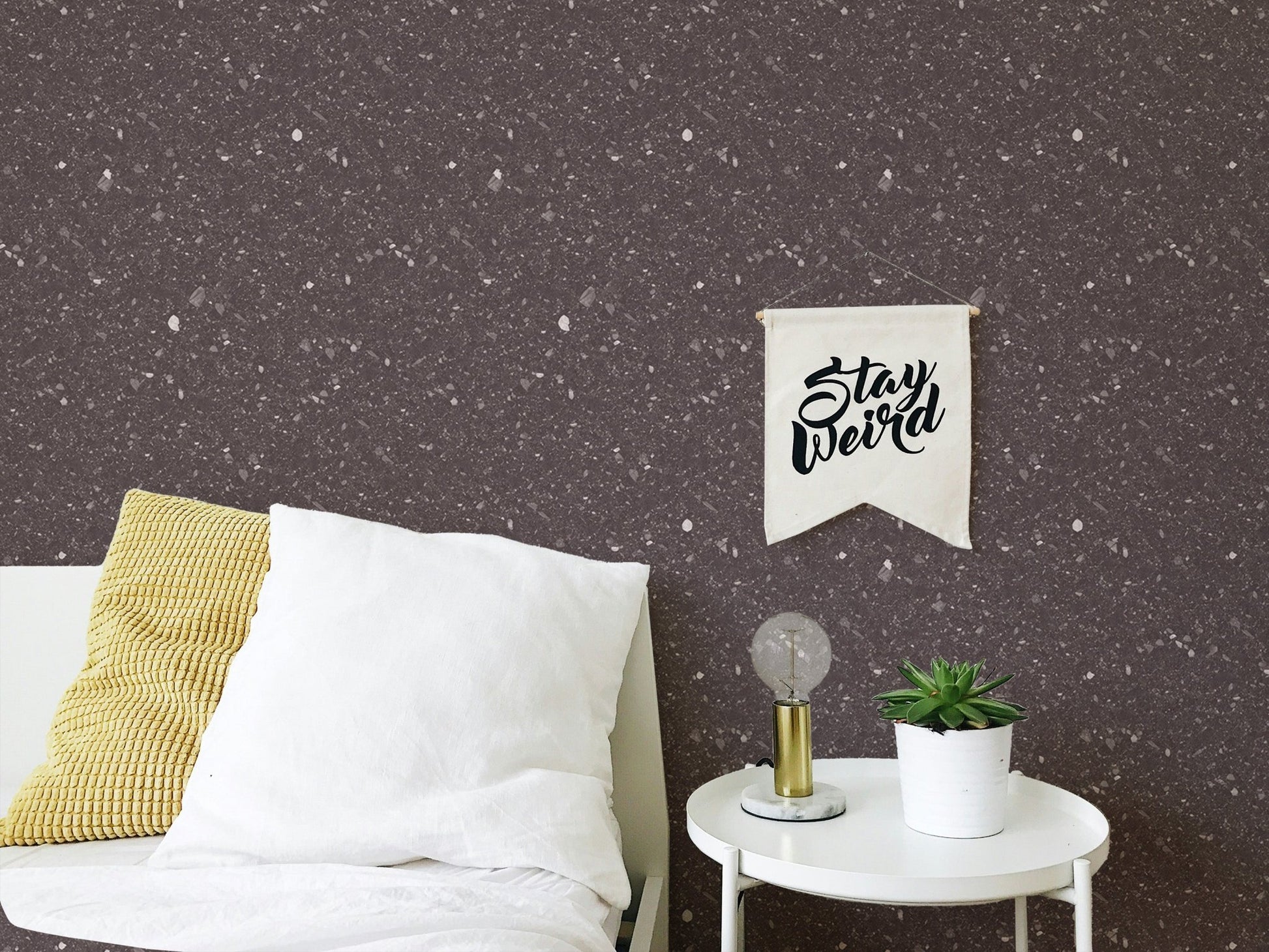Dark brown speckled wallpaper in a bedroom corner with a white round side table.
