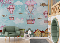 Blue sky aerial wall mural featuring pink balloons and a green armchair in a playroom.