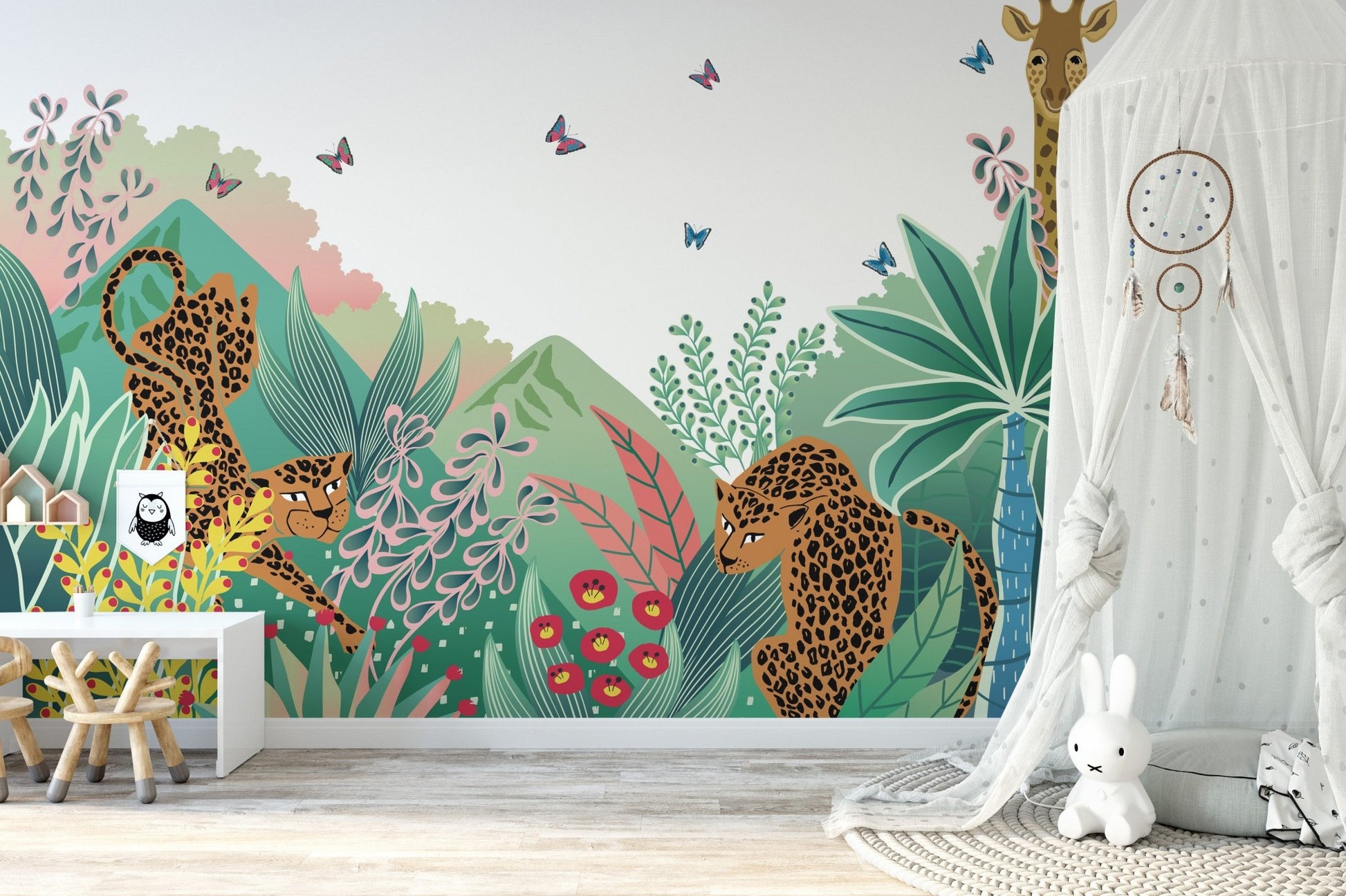 Leopard and butterfly tales wall mural behind a white dreamcatcher in a bright nursery.