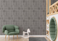 Square grey tile wallpaper in a kids play area with a green chair.