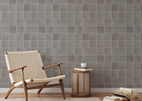 Textured ceramic grey tiles wallpaper in a reading area with a wooden chair.