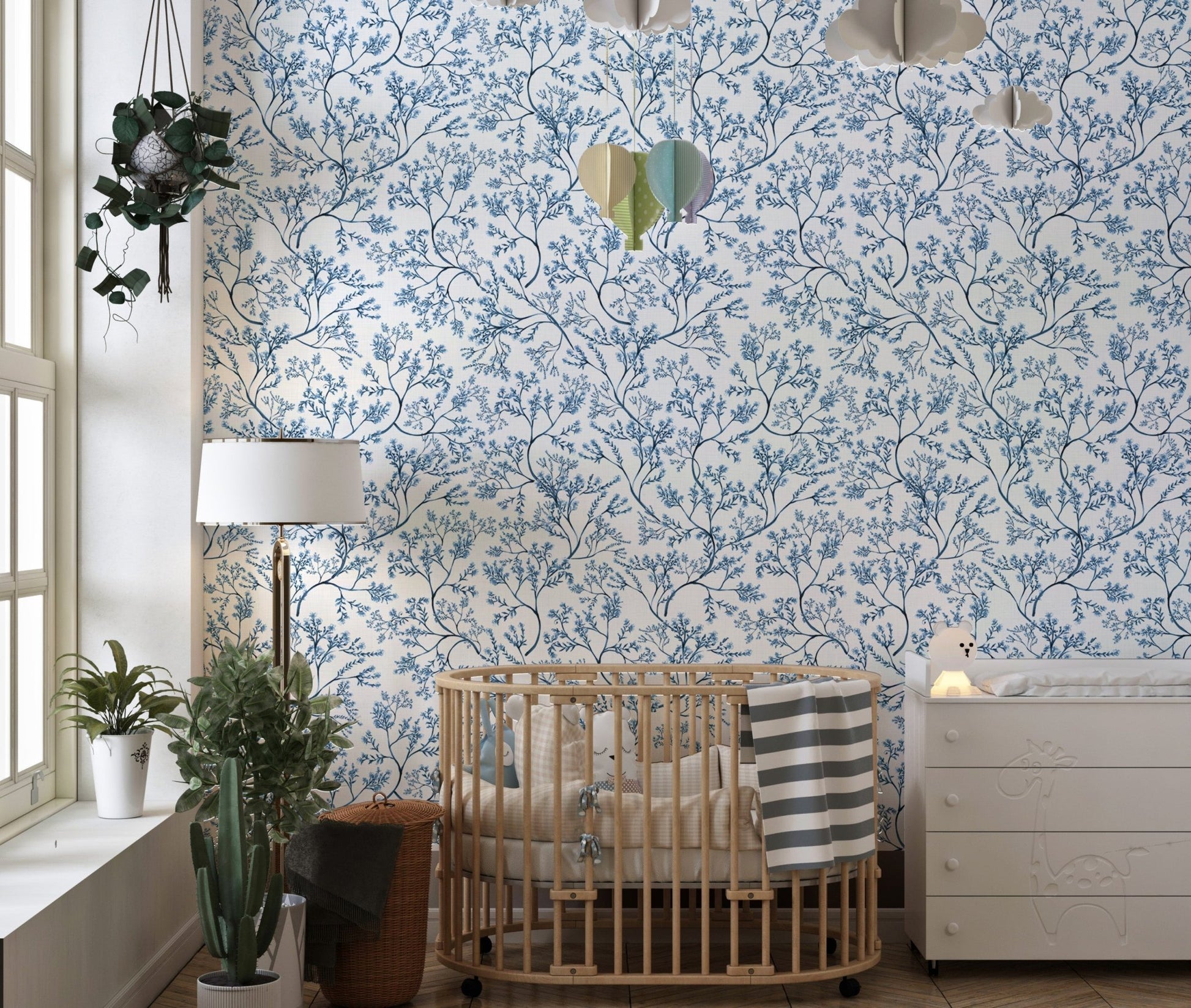 Blue flower wallpaper in a nursery with a wooden crib and white dresser