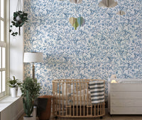 Blue flower wallpaper in a nursery with a wooden crib and white dresser