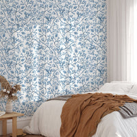 Chinoiserie wild flower wallpaper in a bedroom with a white bed and brown throw