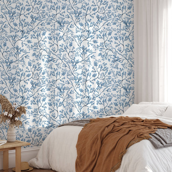 Chinoiserie wild flower wallpaper in a bedroom with a white bed and brown throw
