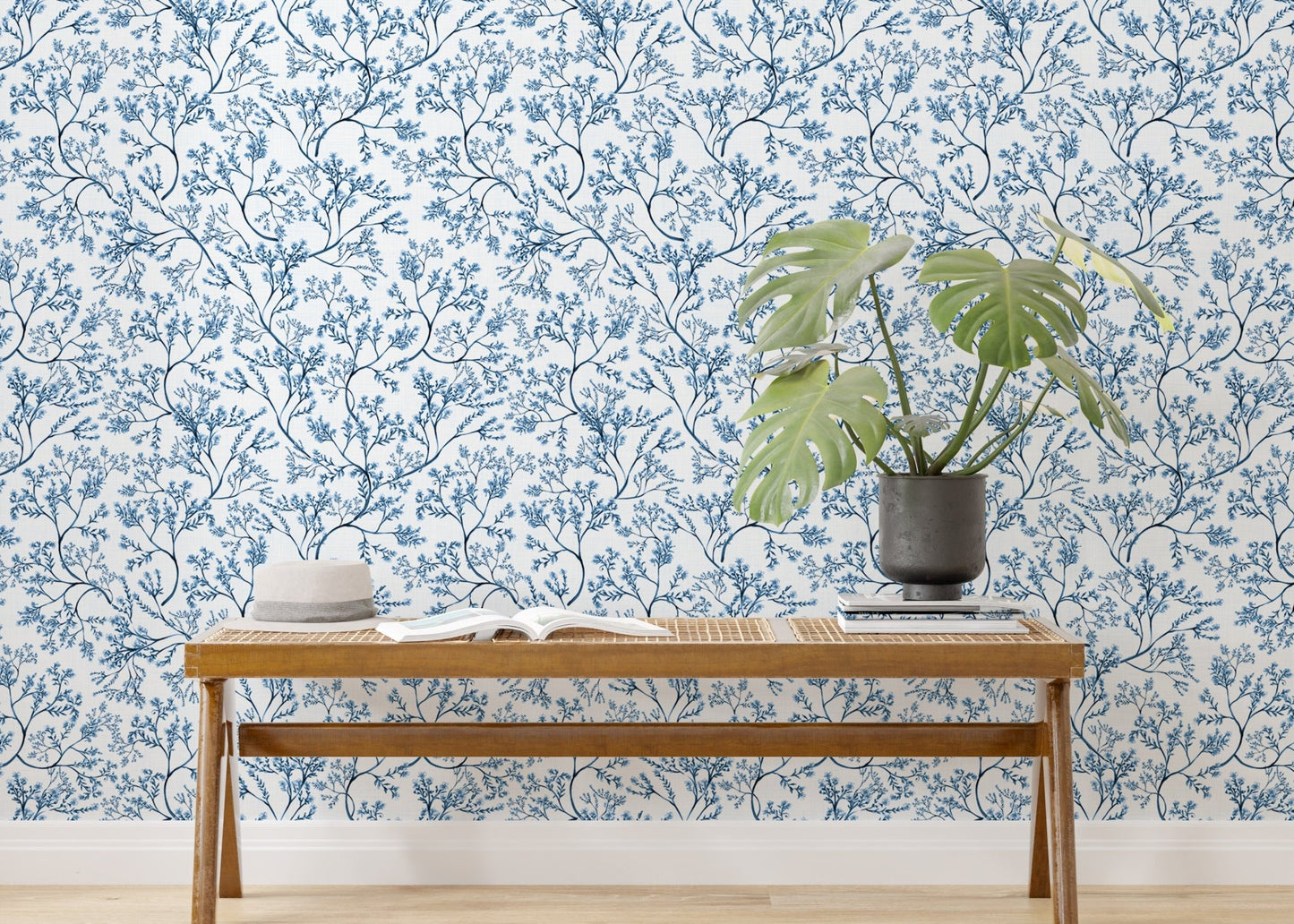 Blue botanical wallpaper behind a wooden console table with a green plant
