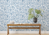 Blue botanical wallpaper behind a wooden console table with a green plant