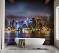 Night city skyline wall mural behind a white bathtub in a minimalist bathroom.