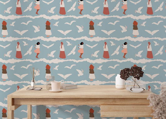 Coastal wallpaper with white seagulls and blue waves behind a light wood desk.