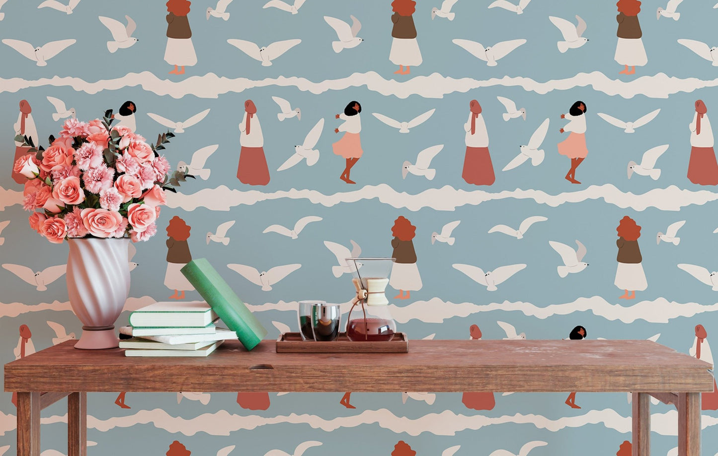 Coastal wallpaper with bird illustrations behind a wooden bench and pink flowers.