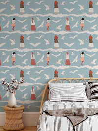 Bedroom wallpaper with flying birds and blue waves behind a child's bed.