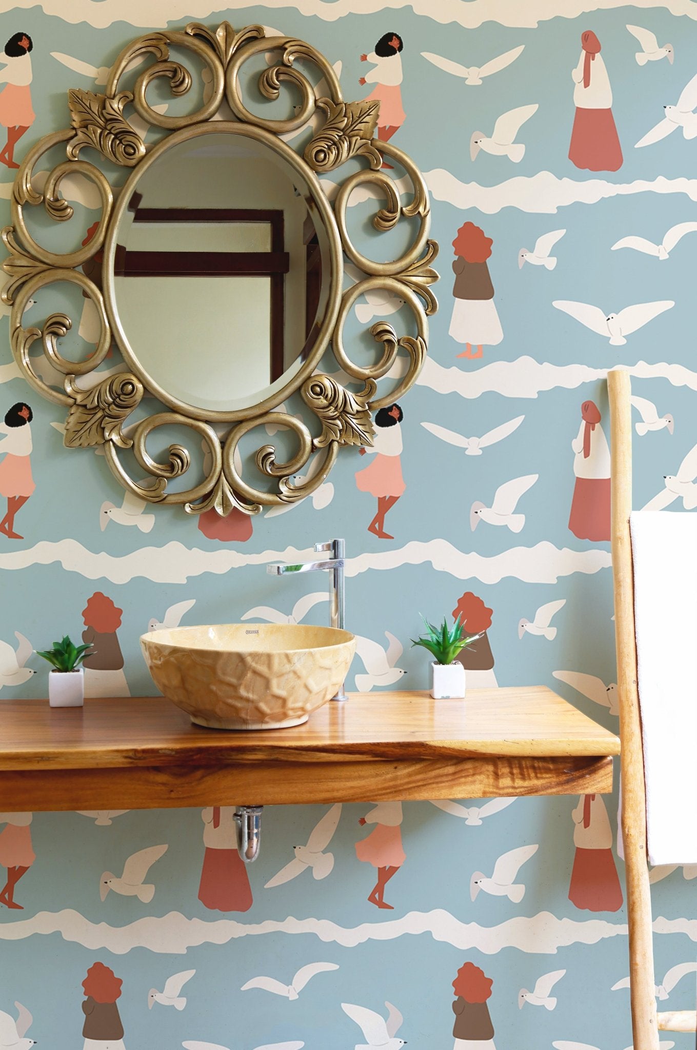 Wallpaper with blue and white wave patterns behind a bathroom vanity and mirror.