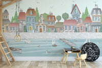 Coastal town wallpaper mural with pastel houses and calm blue water.