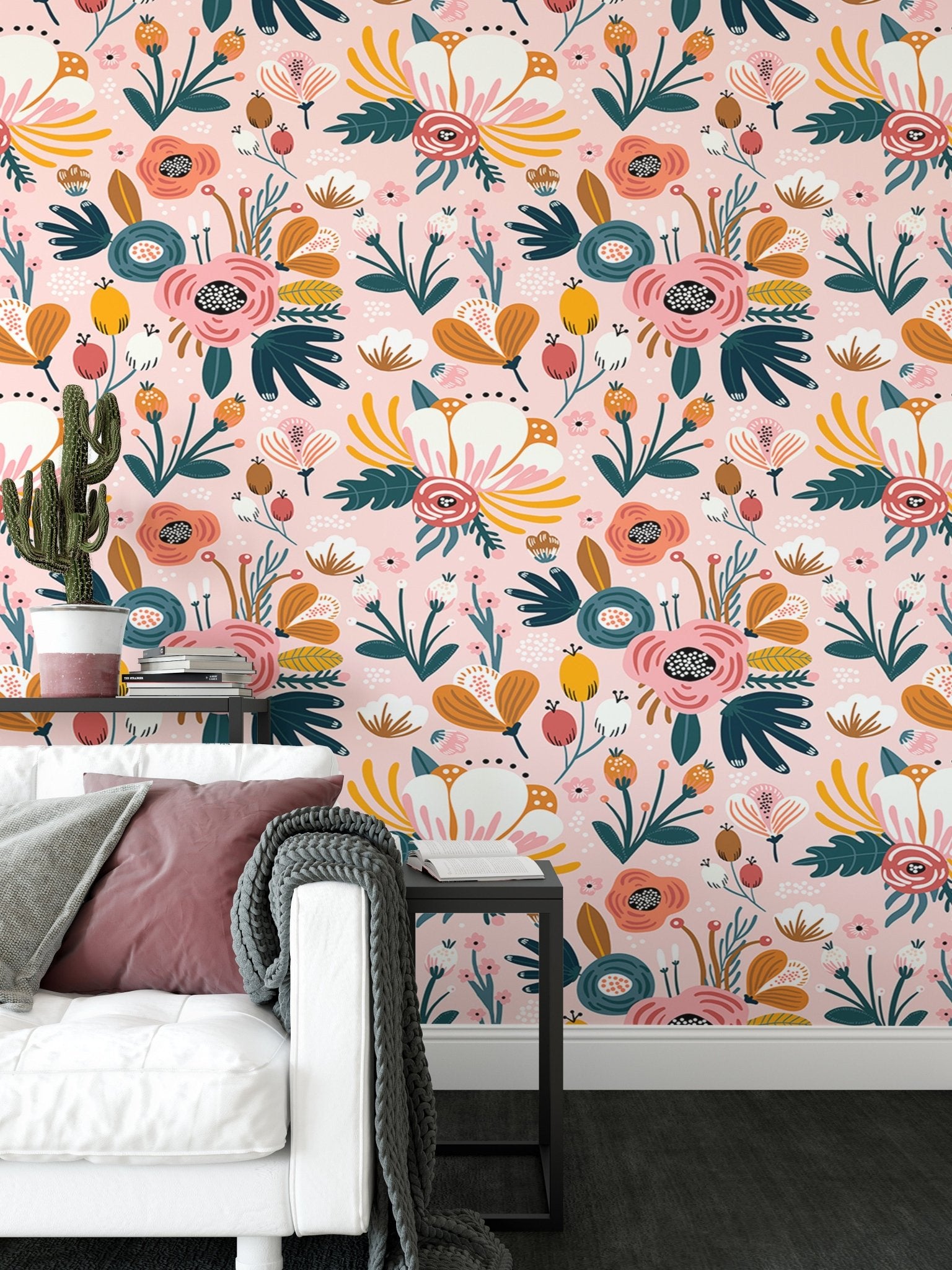 Pink floral pattern wallpaper behind white sofa and grey cushions in living space.