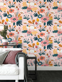 Pink floral pattern wallpaper behind white sofa and grey cushions in living space.