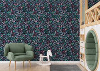Botanical leaves wallpaper pattern in a playroom featuring a green armchair and wooden toys.