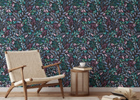 Dark botanical leaves wallpaper in a minimalist room with a tan leather chair.