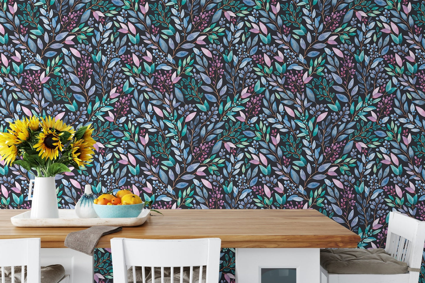 Dark floral leaves wallpaper backdrop for a wooden dining table with white chairs.