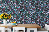 Dark floral leaves wallpaper backdrop for a wooden dining table with white chairs.