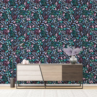 Patterned leaves wallpaper behind a mid-century modern wooden sideboard.