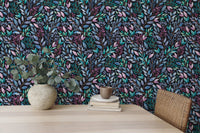 Hand painted leaves wallpaper behind a light wood desk and potted plant.