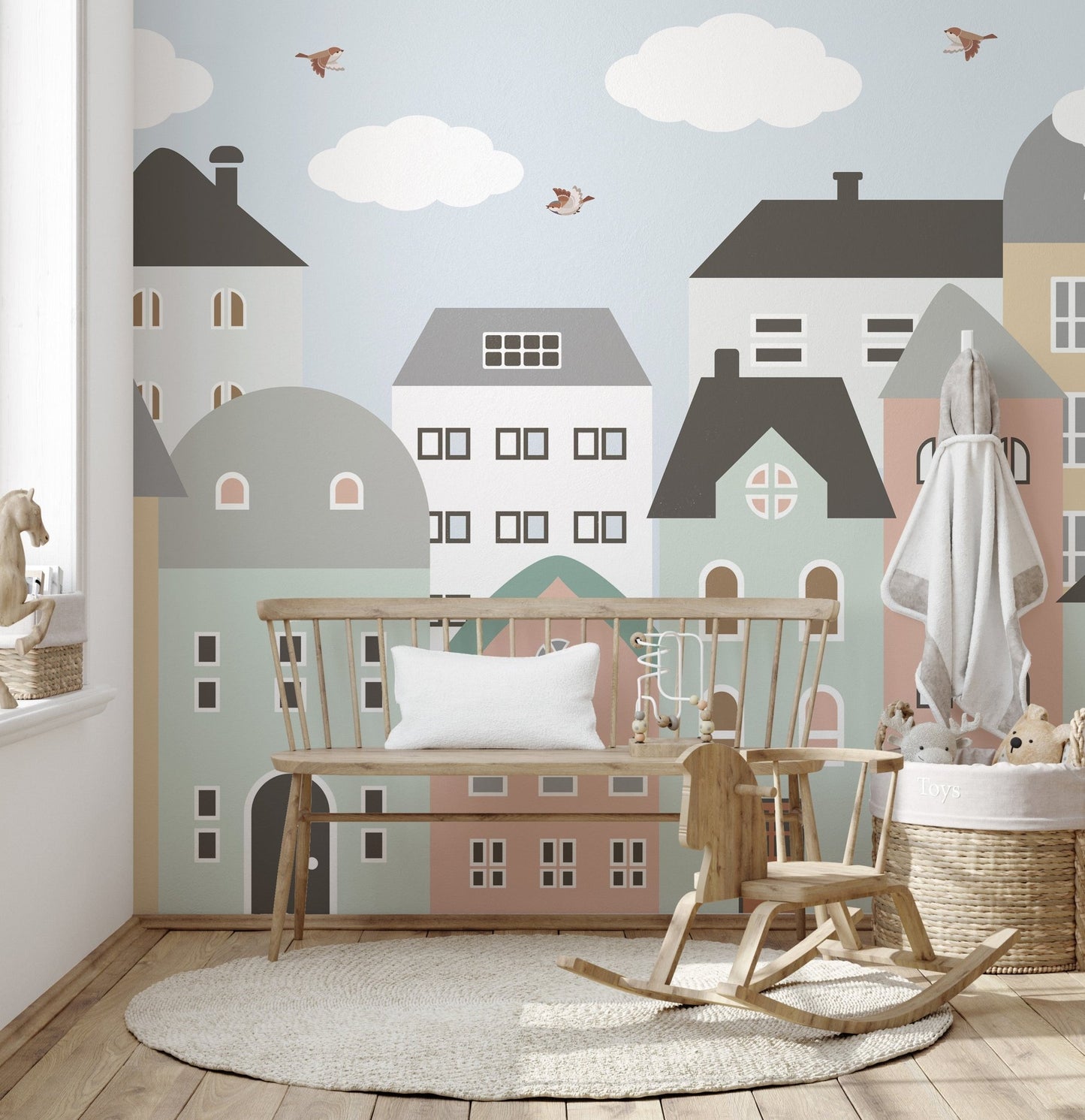 Urban city houses wall mural behind a wooden bench and rocking horse in a play area.