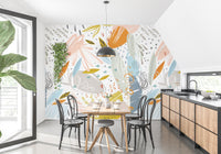 Bright dining area featuring abstract leaf wall mural behind wooden table.