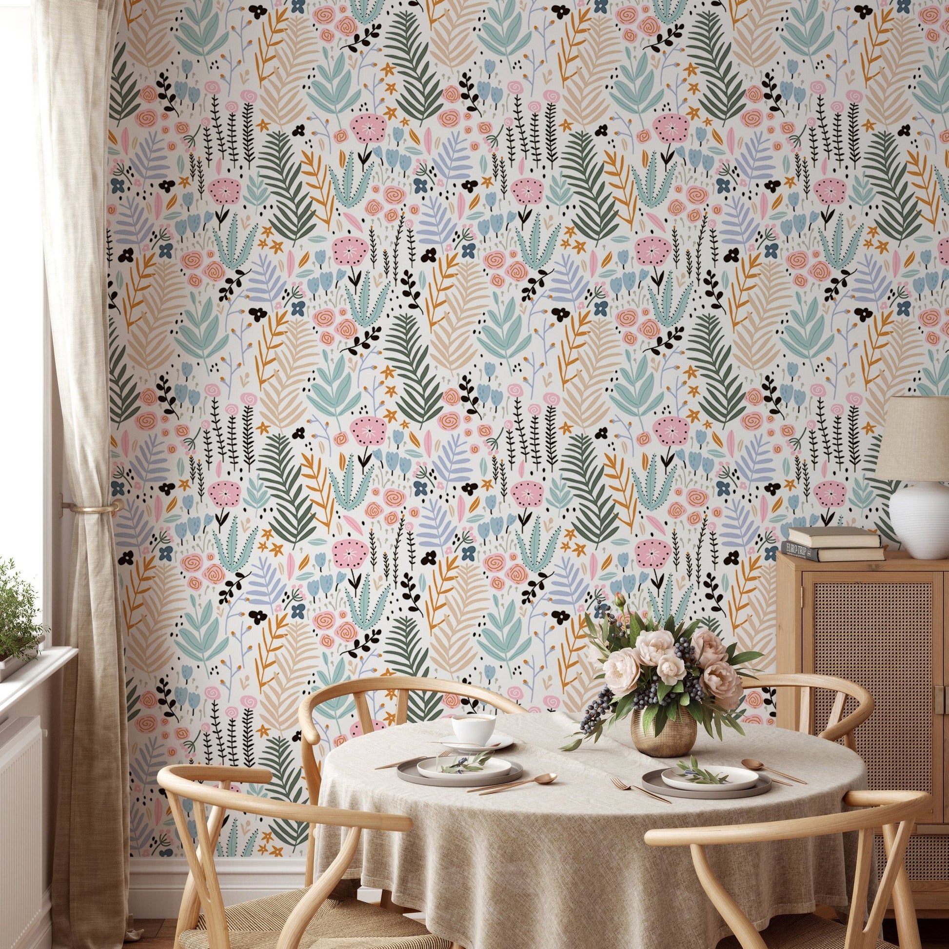 Round dining table with chairs set against a pastel leaves print wallpaper.