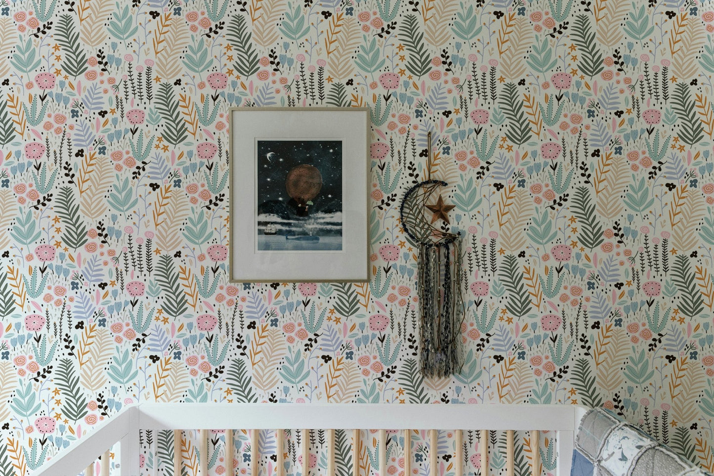 Nursery featuring floral wallpaper with pastel leaves behind a white crib.