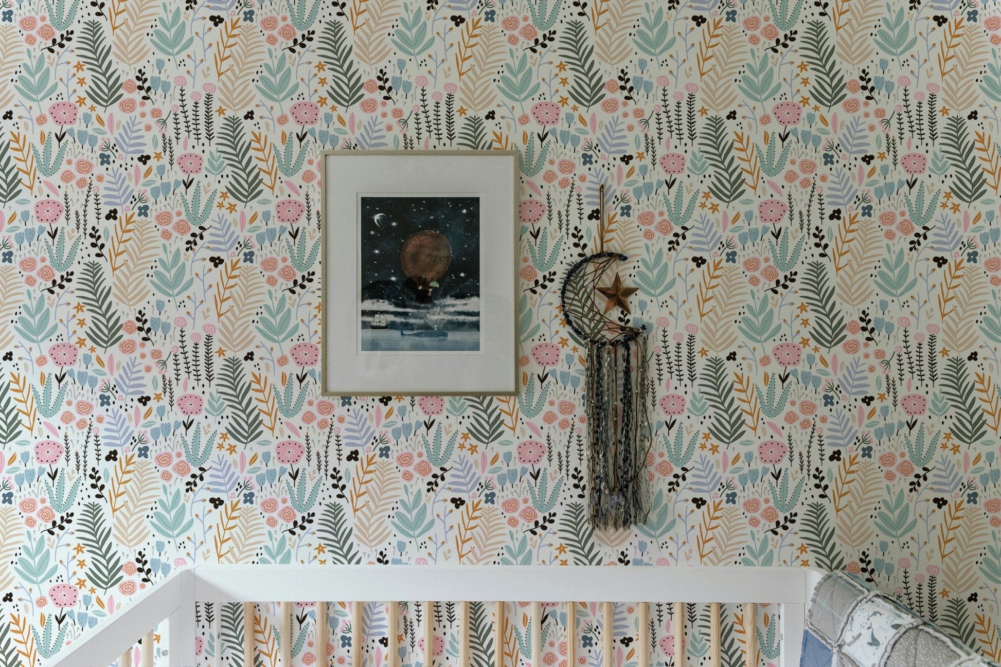 Nursery featuring floral wallpaper with pastel leaves behind a white crib.