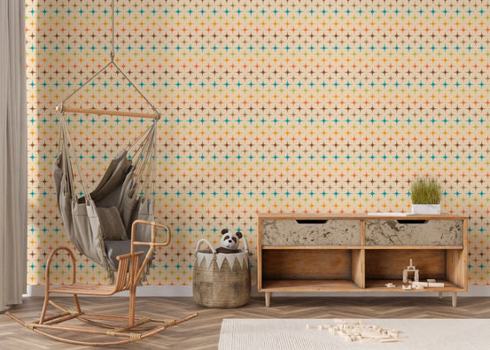 Retro starburst wall mural in a nursery with a hanging chair and wooden console.
