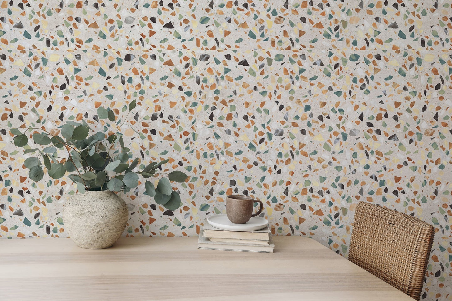Home office desk with green plants and colorful mosaic texture wallpaper.