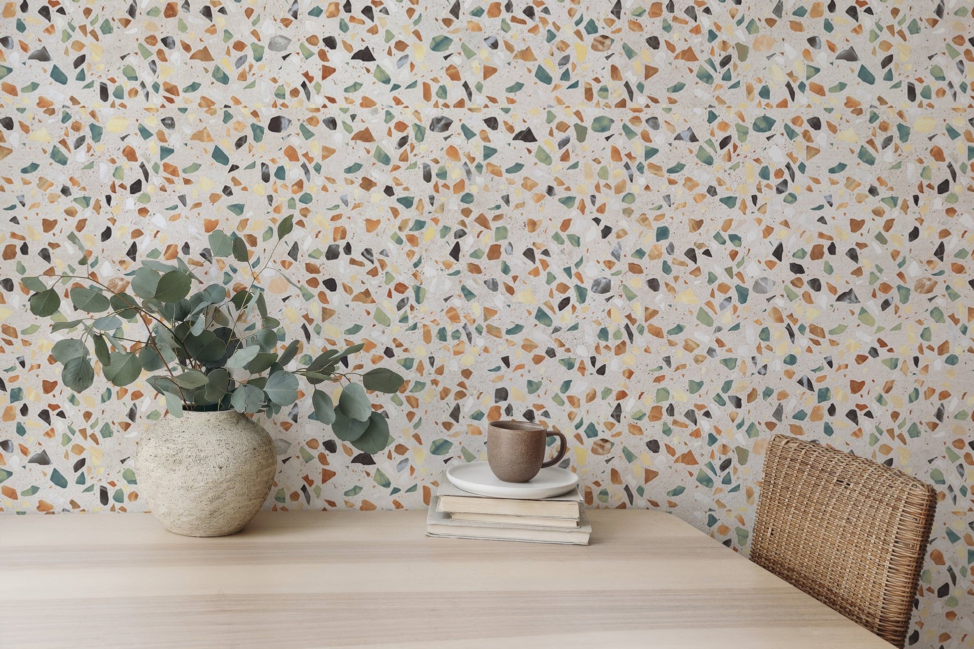 Home office desk with green plants and colorful mosaic texture wallpaper.