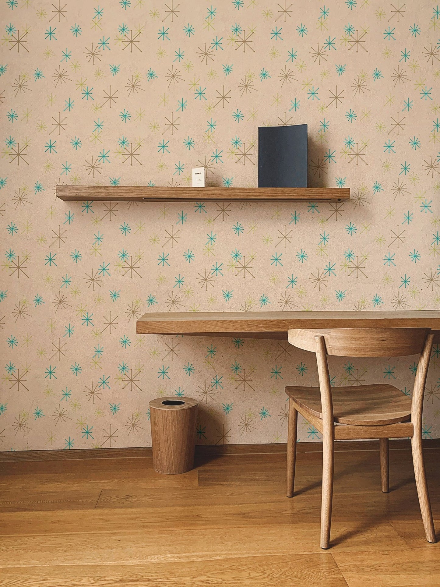 Home office setup with a floating wooden shelf on a colorful snow fleck wall mural.